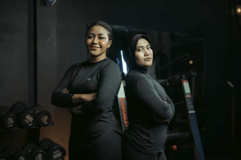 Duas treinadoras de braços cruzados numa academia